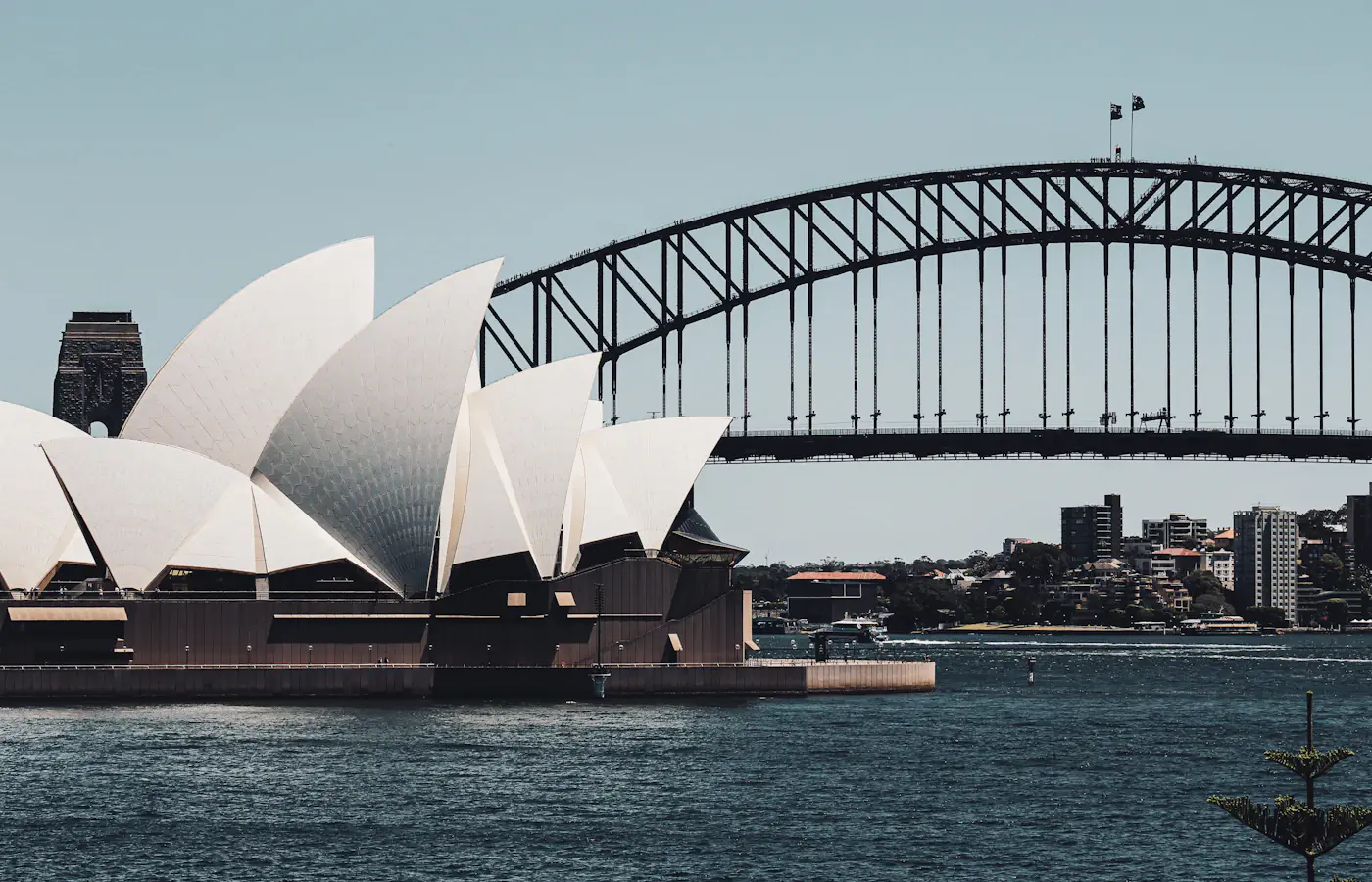 Sydney Opera House accanto al porto con il Sydney Harbour Bridge dietro.