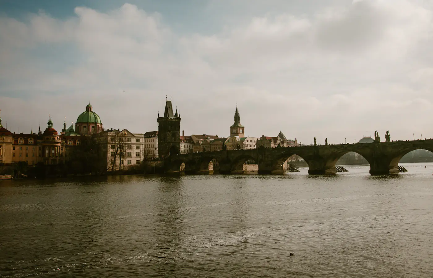 Charles Bridge spanning the Vltava River beside the Old Town Bridge Tower in Prague.