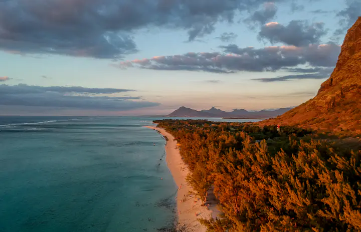 Aerial photo of trees, a beach and turquoise water at Le Morne, Mauritius.