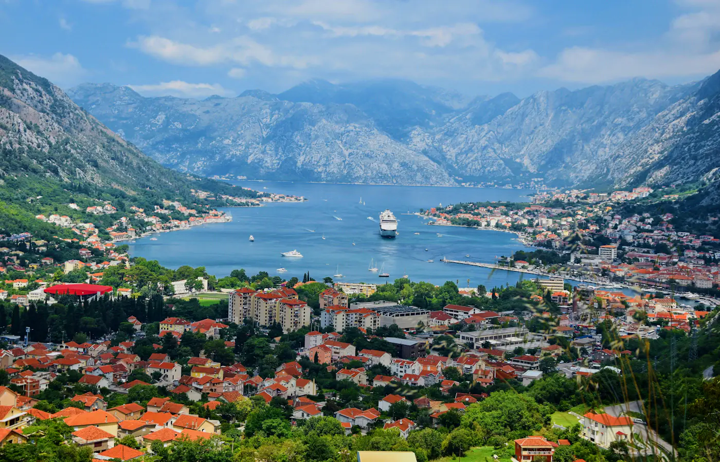 Rot gedeckte Gebäude von Kotor unter den Bergen rund um die Bucht von Kotor, Montenegro