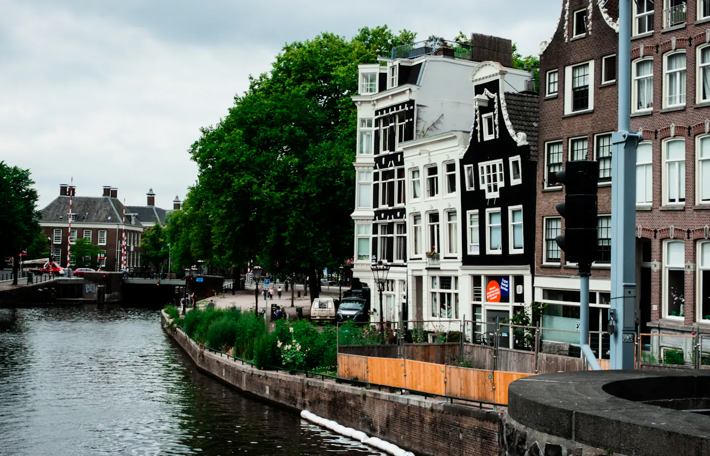 Tree-lined Amsterdam canal with traditional houses and a footbridge