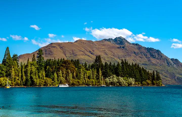 Blauw meerwater, beboste kustlijn en bergen bij Queenstown in Nieuw-Zeeland