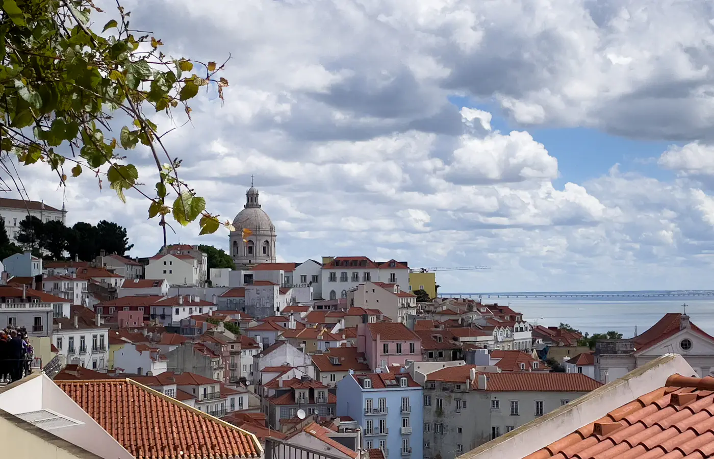Red rooftops of Lisbon's Alfama district, with the National Pantheon and the Tagus beyond.