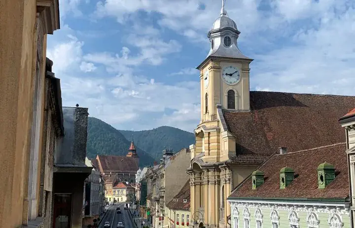 Oude gebouwen en een beboste heuvel die boven het centrum van Brașov, Roemenië, uitrijst