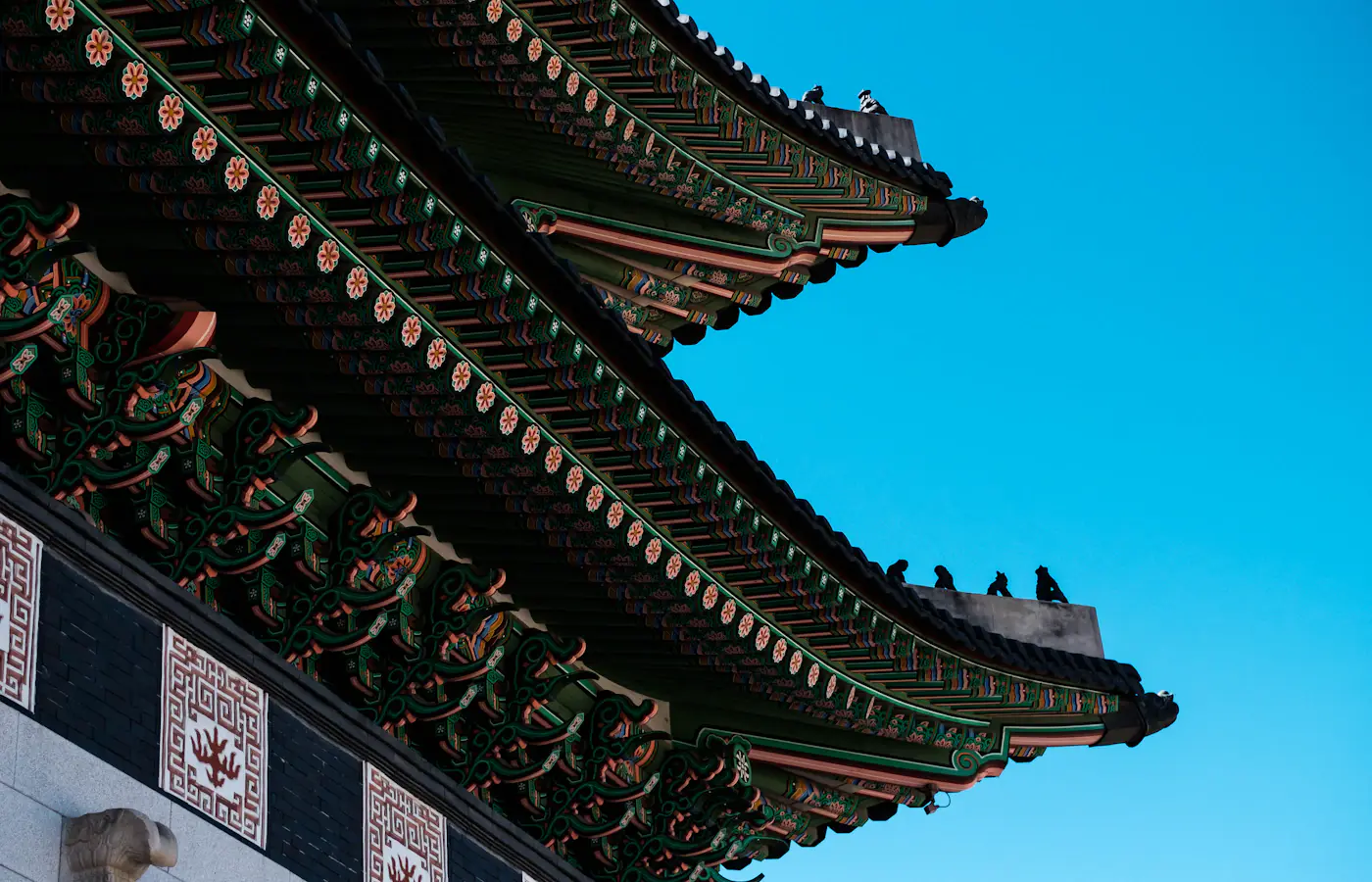 Ornate palace roof eaves under a blue sky at Gyeongbokgung in Seoul, South Korea