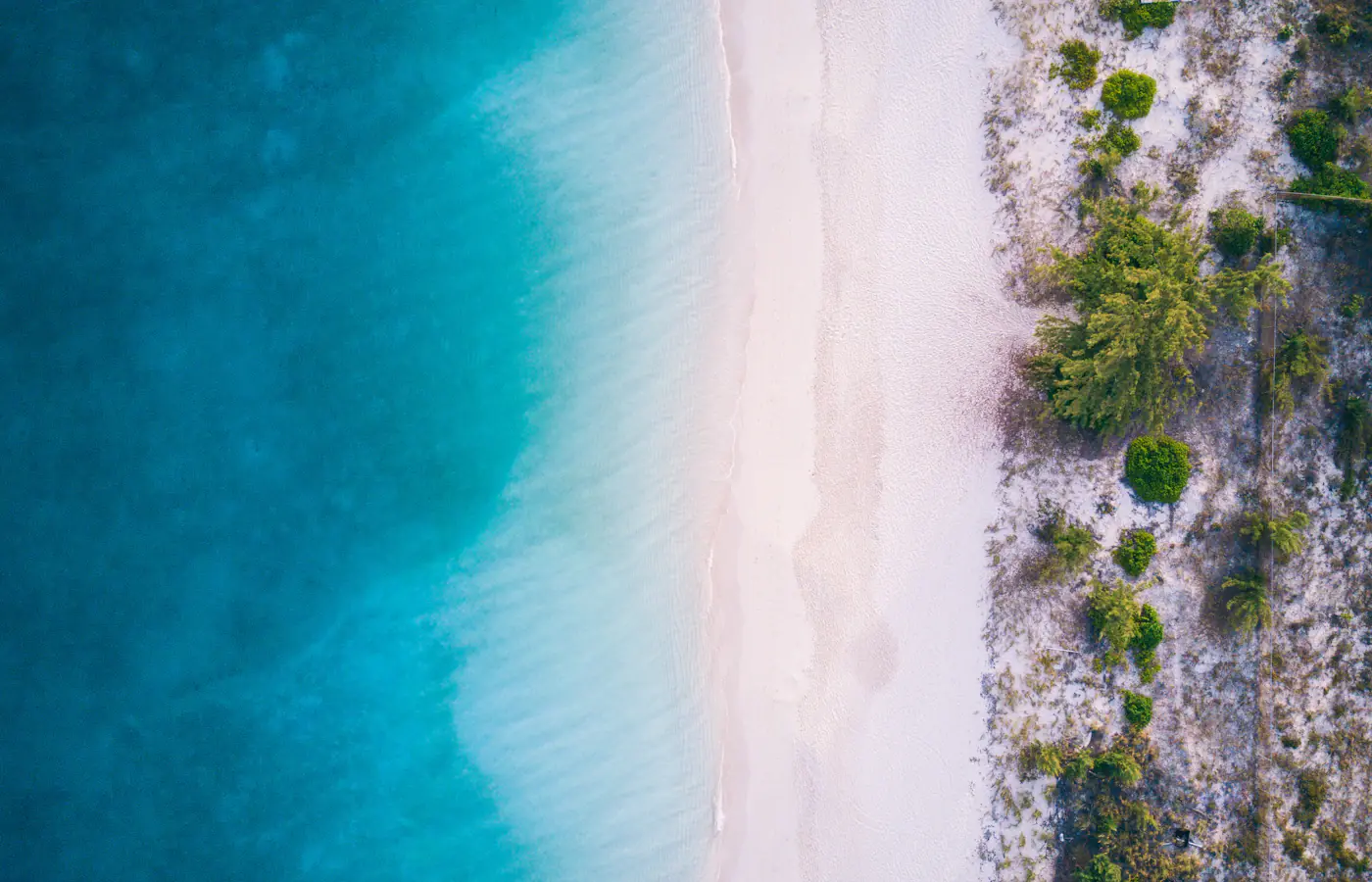 Luftaufnahme des weißen Sands und des flachen türkisfarbenen Wassers der Grace Bay auf den Turks- und Caicosinseln