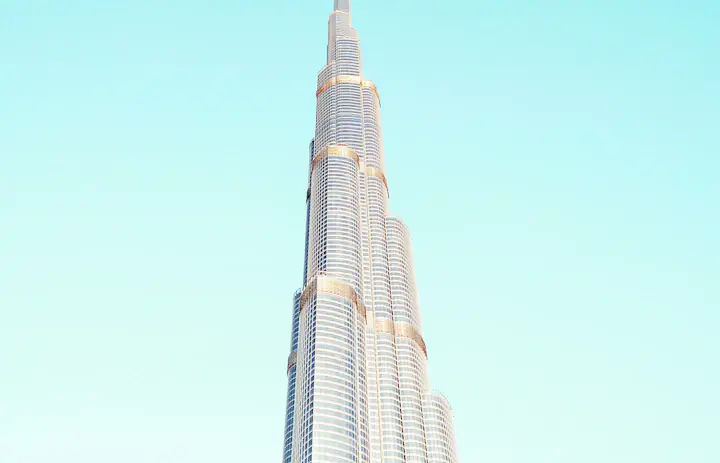 Burj Khalifa's stepped glass tower against a pale blue Dubai sky
